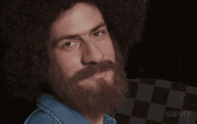 a man with a beard and an afro is making a funny face