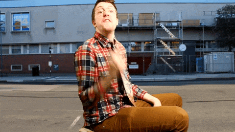 a man in a plaid shirt sits on the sidewalk in front of a building that has the number 4 on the window