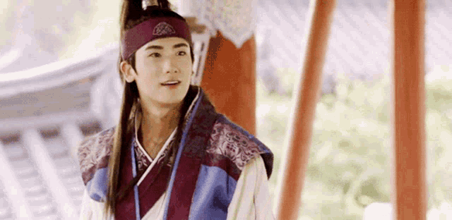 a young man wearing a headband and a traditional korean outfit