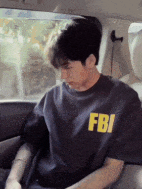 a man wearing a fbi shirt is sitting in a car