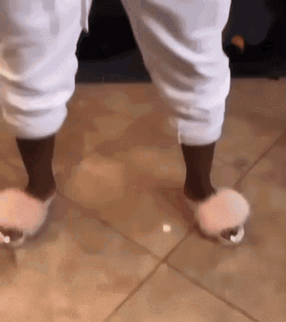 a person wearing a pair of pink fluffy slippers on a tiled floor .