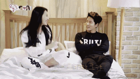 a man and a woman are sitting on a bed and the man is wearing a shirt that says ritj