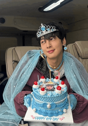 a man wearing a tiara and veil is holding a cake that says happy 2nd day