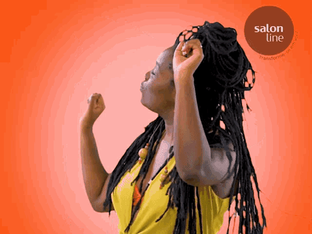 a woman with dreadlocks is dancing in front of an orange background with a salon line logo
