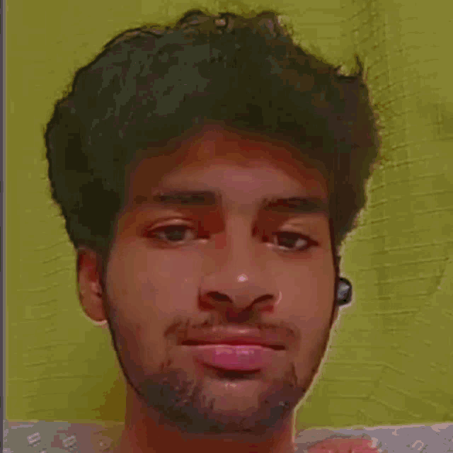 a young man with a beard is making a funny face in front of a yellow background .