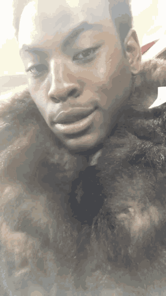 a close up of a man 's face with a fur coat around his neck