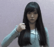 a woman with long black hair is pointing her finger at the camera
