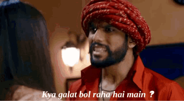 a man wearing a red shirt and a turban is talking to a woman