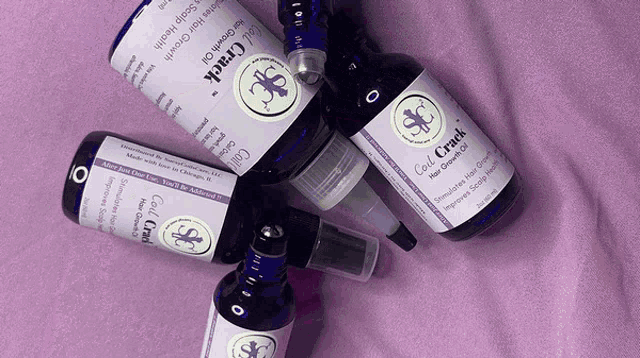several bottles of curl crack hair growth oil are on a purple surface