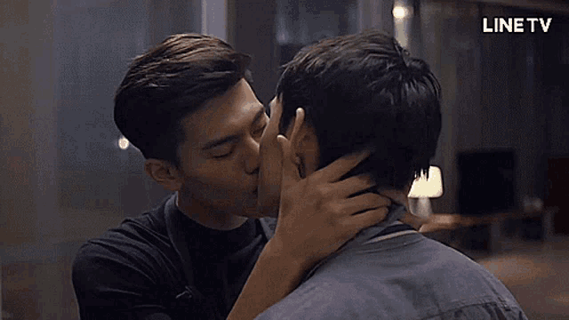 two men kissing in front of a sign that says linetv
