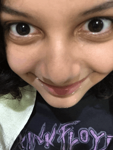 a young girl wearing a pink floyd shirt smiles for the camera