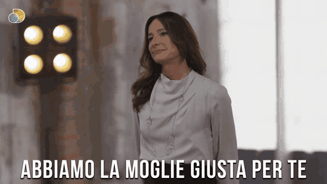a woman in a white shirt is standing in front of a sign that says abbiamo la moglie giusta per te