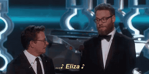 two men are standing next to each other on a stage and one of them is talking into a microphone .