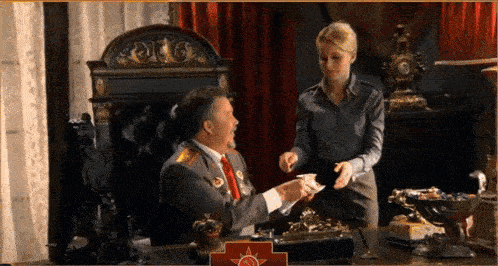 a man and a woman are sitting at a desk with a red cross on the desk