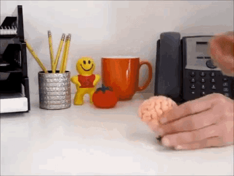 a person is holding a piece of meat on a desk in front of a telephone
