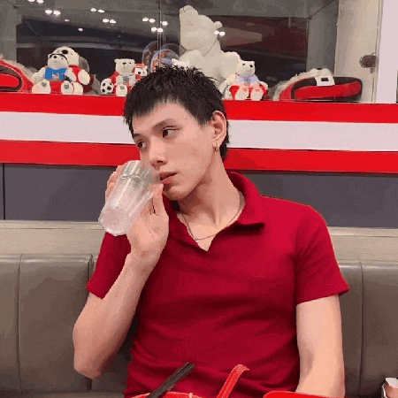 a man in a red shirt is drinking from a plastic cup .