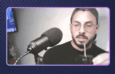 a man with glasses and a beard is smoking a cigarette in front of a microphone