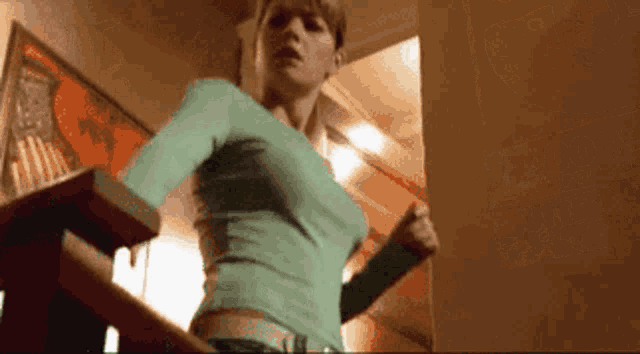 a woman in a green shirt is running down a set of stairs