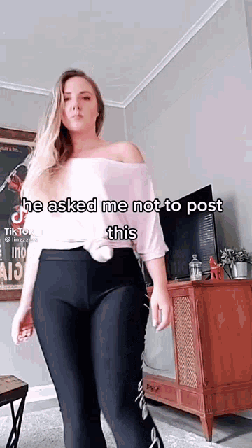 a woman is standing in a living room with a caption that says " he asked me not to post this "