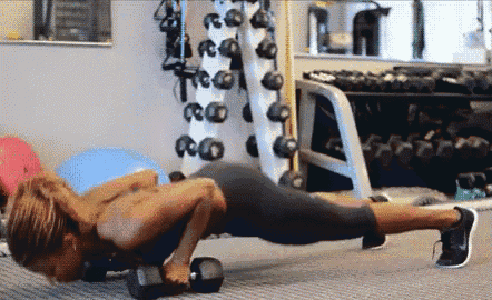 a woman is doing push ups with a dumbbell