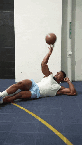 a man is laying on the floor holding a basketball in front of a no parking sign