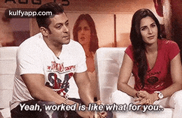 a man and a woman are sitting on a couch holding hands and talking .