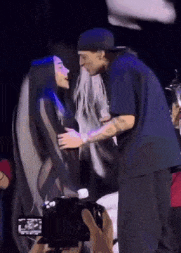 a man and a woman are kissing on a stage while a cameraman takes a picture .
