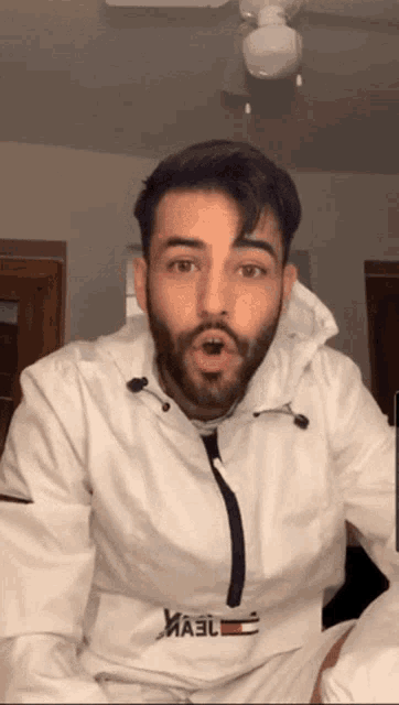 a man with a beard is wearing a white jacket with a tommy hilfiger logo on the front