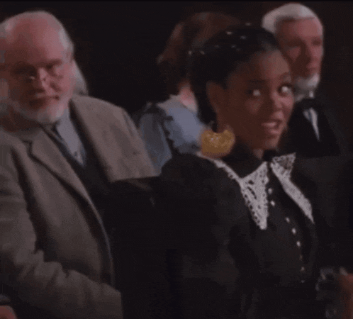 a woman in a black dress is sitting in a row of people