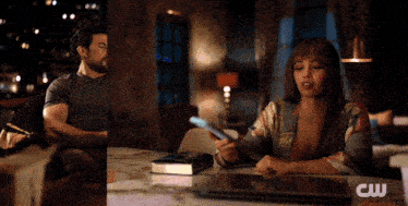 a man and a woman sitting at a table with a cw logo on the bottom