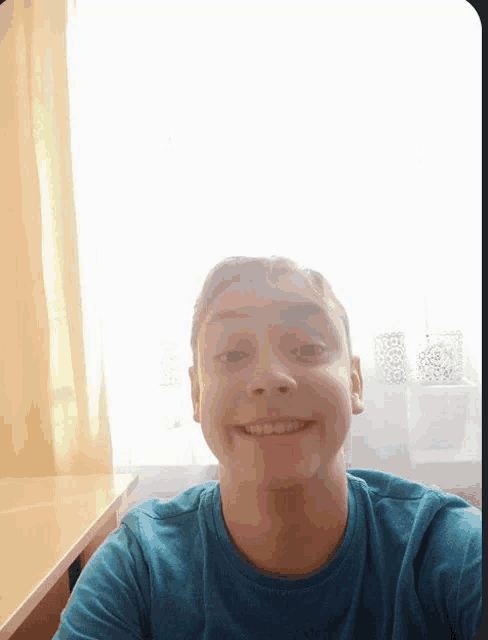 a young man in a blue shirt takes a selfie
