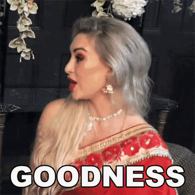 a woman in a red saree with the word goodness written on the bottom