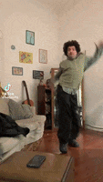 a man is dancing in a living room in front of a couch and table