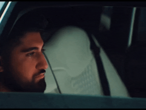 a man with a beard looks out of a car window