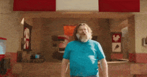 a man with a beard and a blue shirt is standing in front of a chicken restaurant