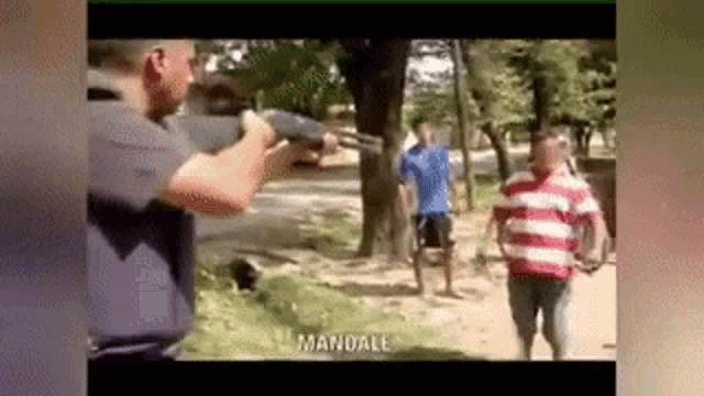 a man is holding a gun in front of a group of men .