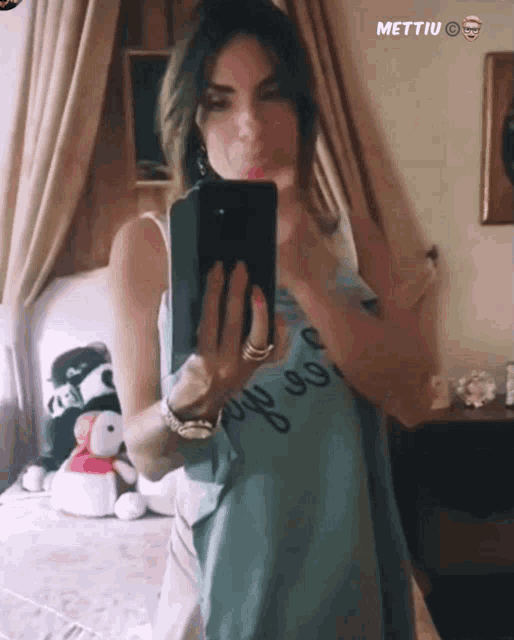 a woman taking a picture of herself in a mirror with mettiu on the bottom
