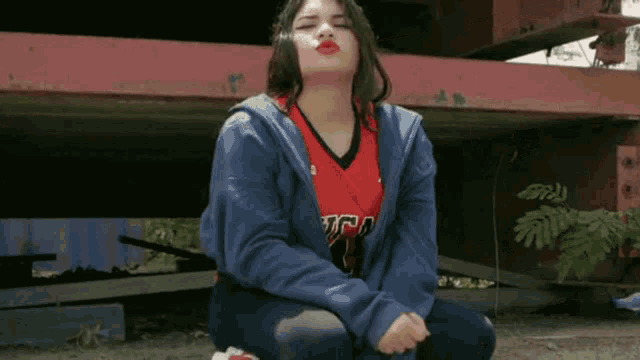 a woman wearing a blue hoodie and a red ucla jersey