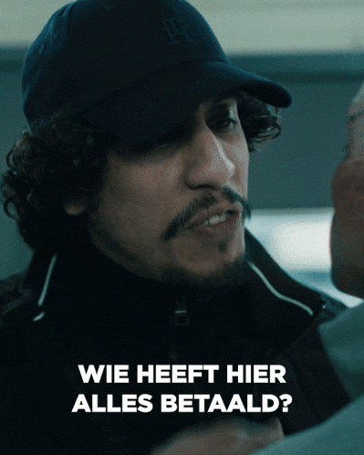 a man wearing a hat says " wie heeft hier alles betaald " on the bottom
