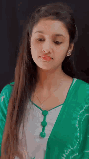 a girl with long hair wearing a green shirt and necklace
