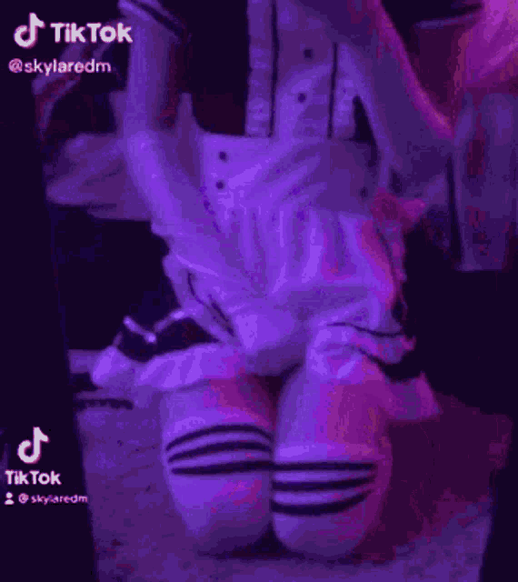 a woman in a white dress is dancing in front of a purple light .