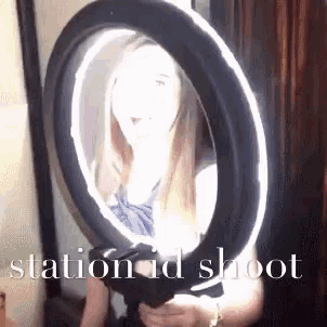 a woman is standing in front of a ring light with the words station id shoot written on the bottom