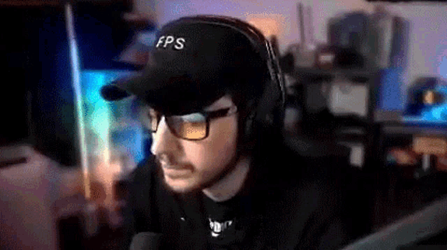 a man wearing a hat and glasses is sitting in front of a computer .