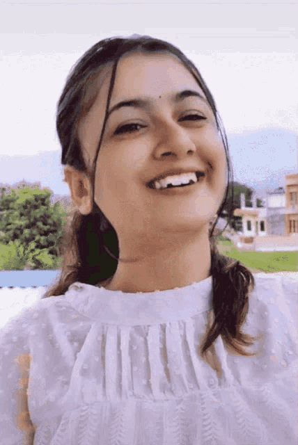 a woman in a white top is smiling and looking to the side