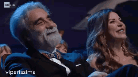 a man with a beard is sitting next to a woman who is smiling and laughing .