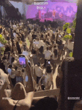a crowd of people at a concert with a sign that says ' @ugurdrums ' on it