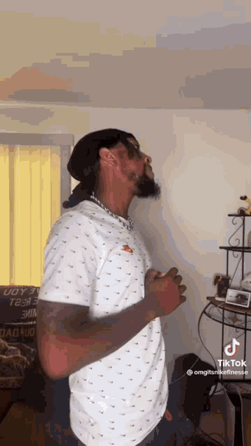 a man is standing in a living room with his arms outstretched .