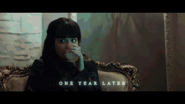 a woman sits on a couch drinking from a cup and the words one year later are visible