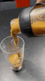 a bottle is being poured into a glass with a few drops of liquid