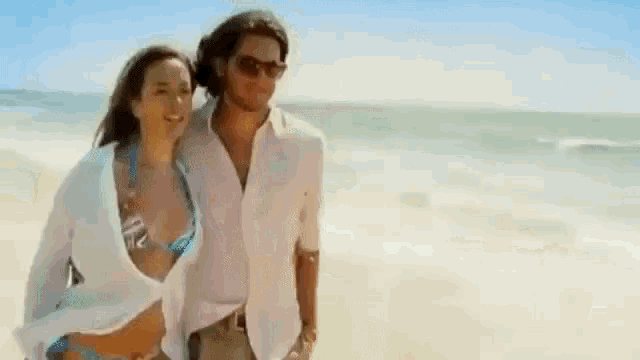 a man and woman are walking on the beach .